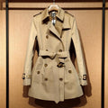 Khaki women's double-breasted trench coat with flight sleeves on a hanger.
