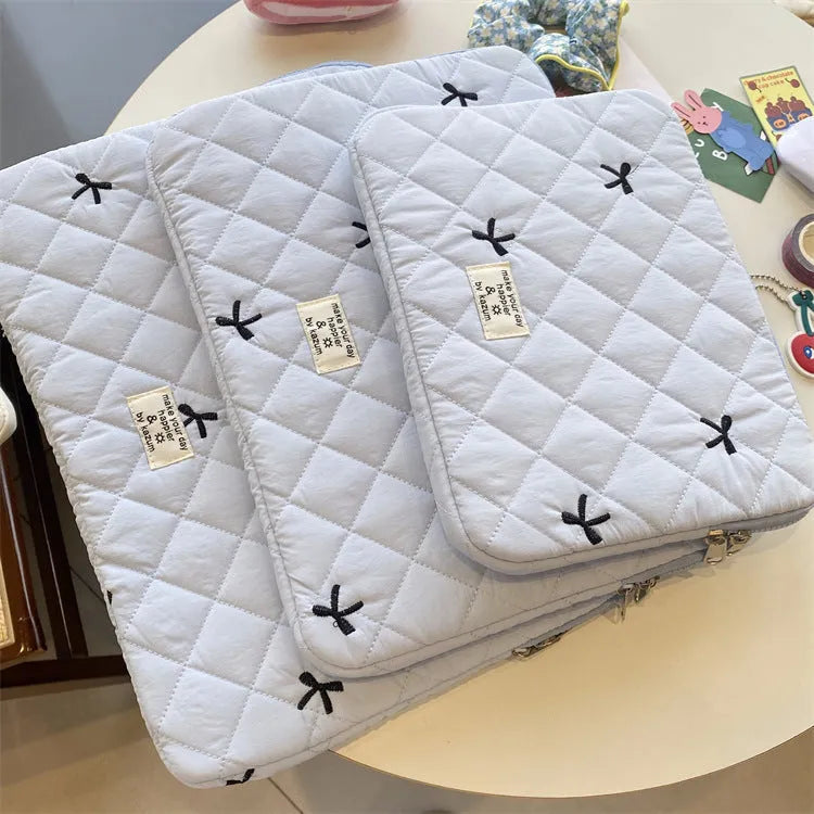 Nylon laptop storage bag with a rhombus-shaped embroidered bow on the front.