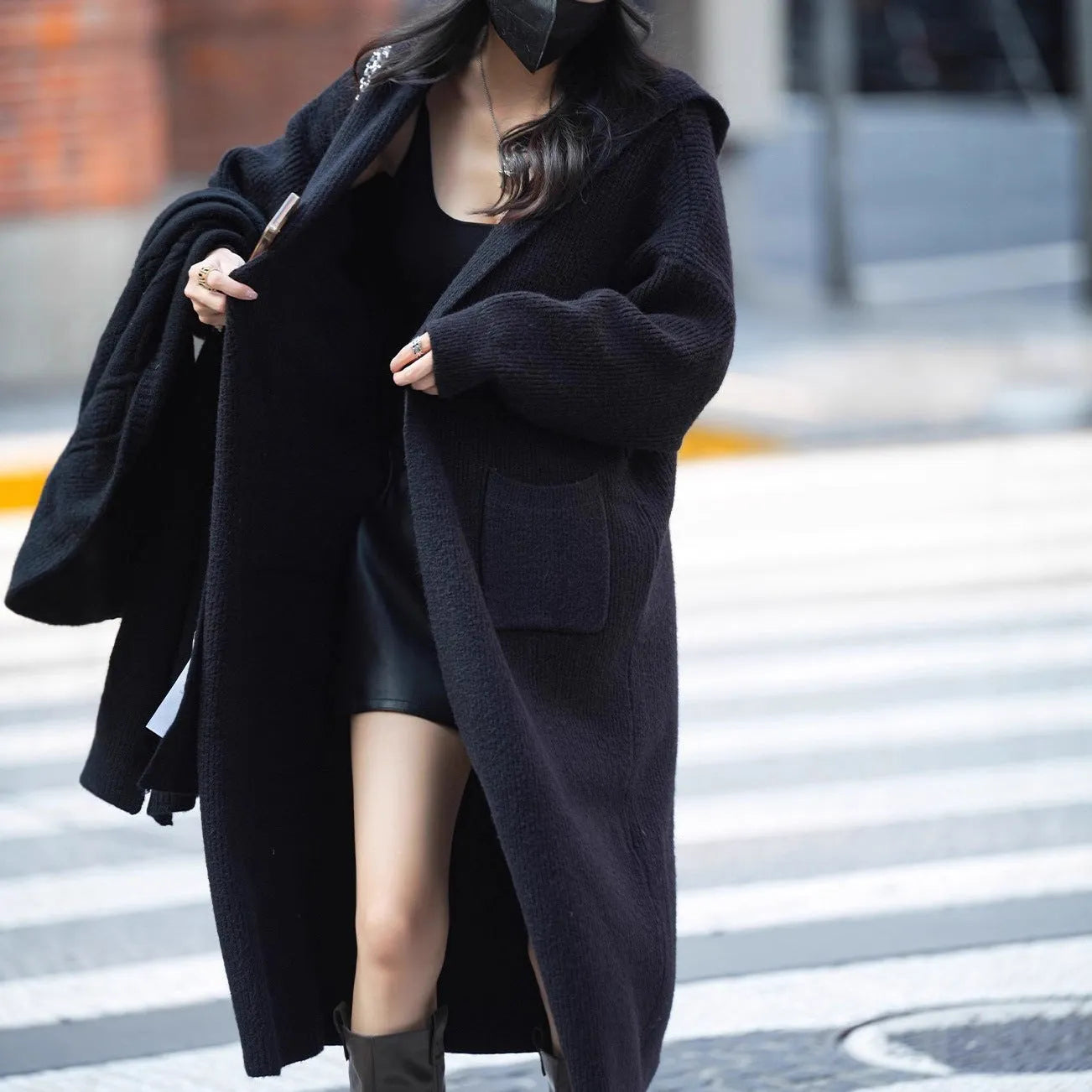 Long grey knitted hooded trench coat shown on a model, cardigan style with long sleeves.