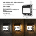Black solar powered doorplate light with digital LED display mounted on brick wall