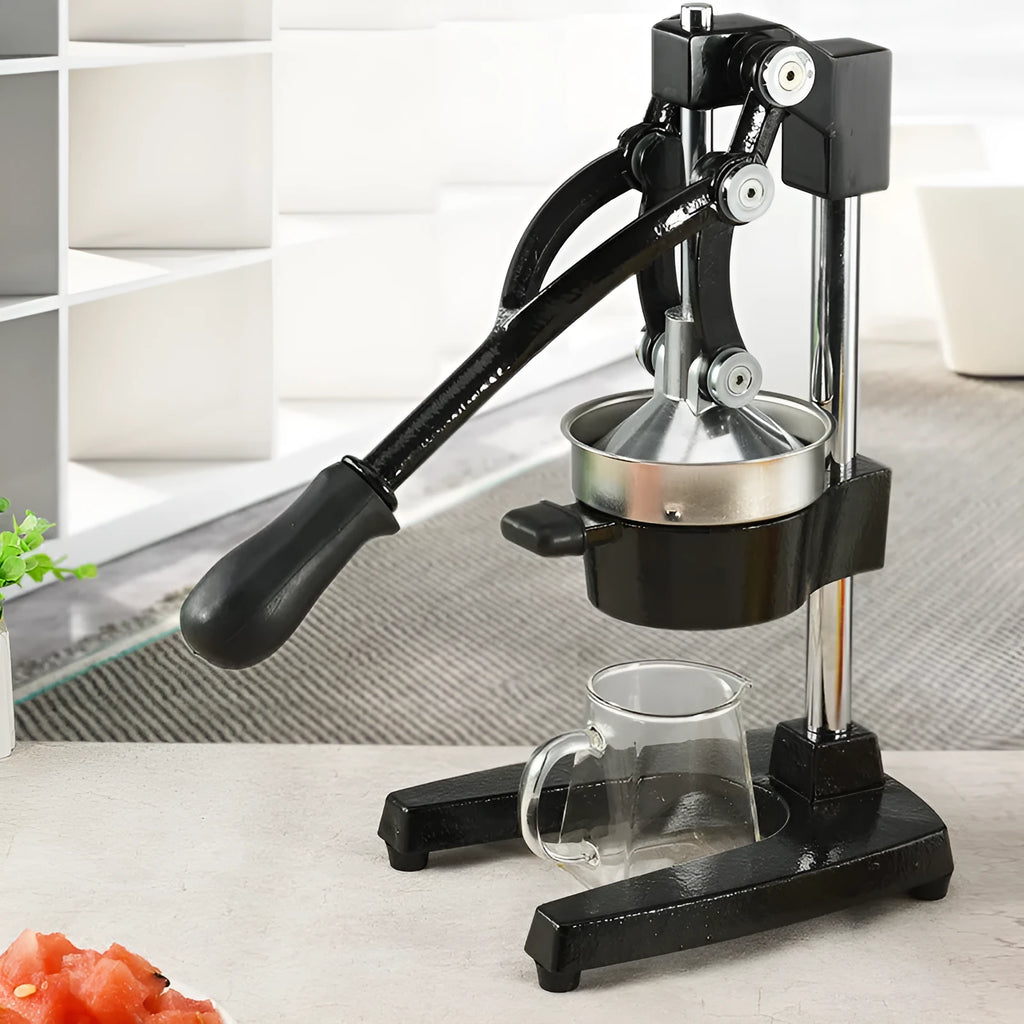 Black and white manual cast iron citrus juicer with stainless steel funnel on kitchen counter