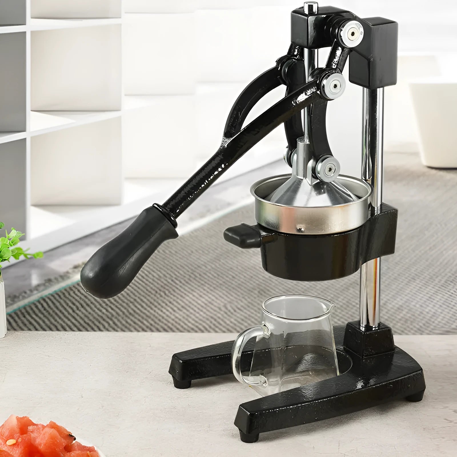 Black and white manual cast iron citrus juicer with stainless steel funnel on kitchen counter