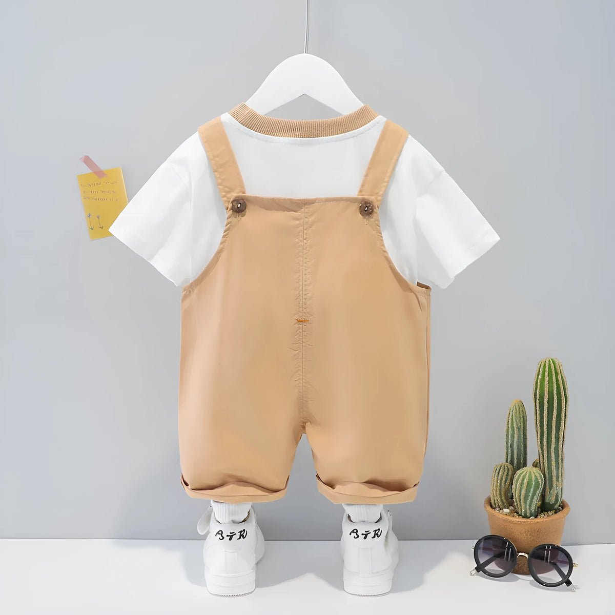 Yellow cotton baby overalls with cartoon prints and openable straps, shown in a Korean-style romper suit design.