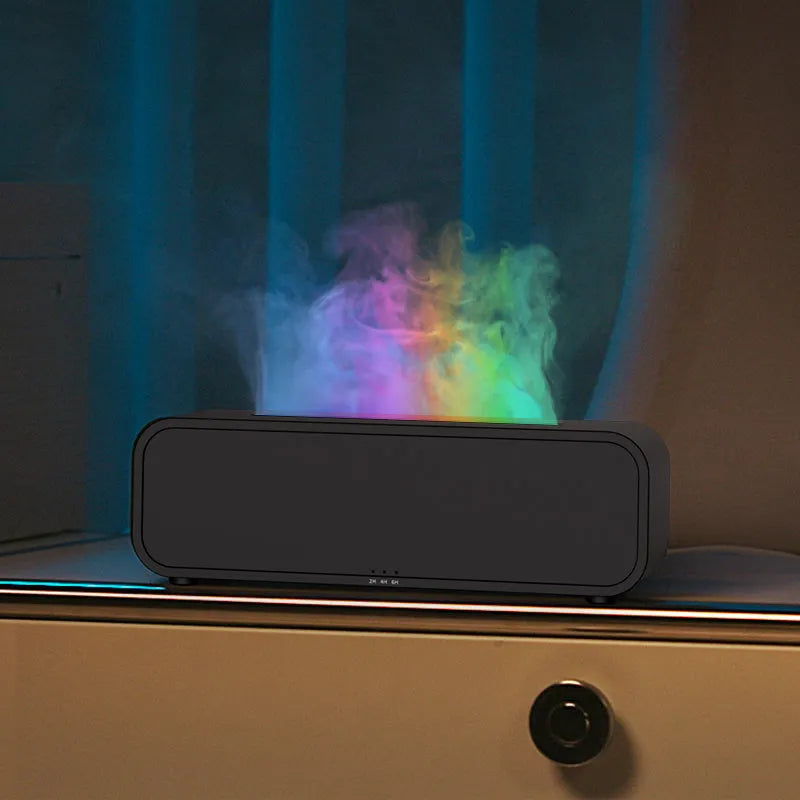 Black aroma diffuser with colour-changing flame light effect and remote control on a table.