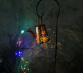 Tapered iron solar garden lamp with butterfly pattern emitting warm white light in a courtyard setting