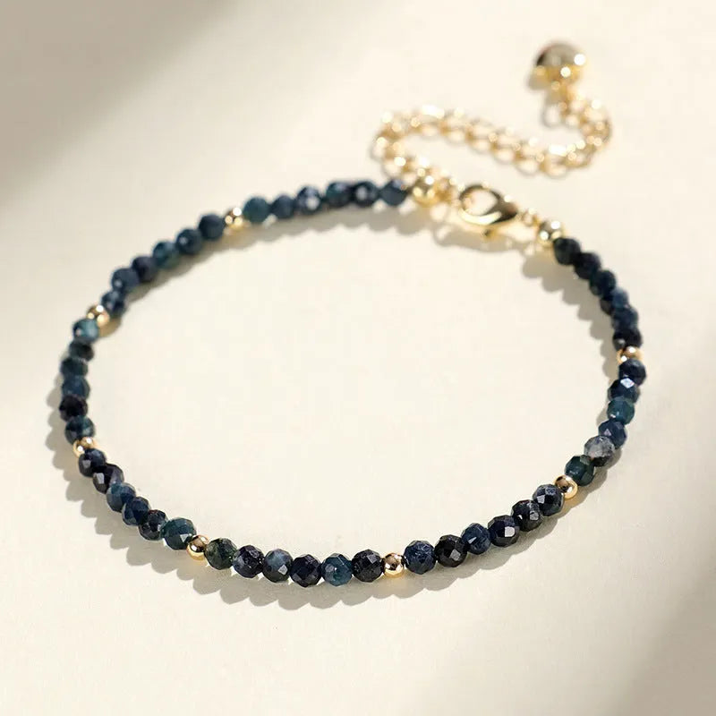 Blue tourmaline bracelet with 3mm beads and spacer beads on a wrist.