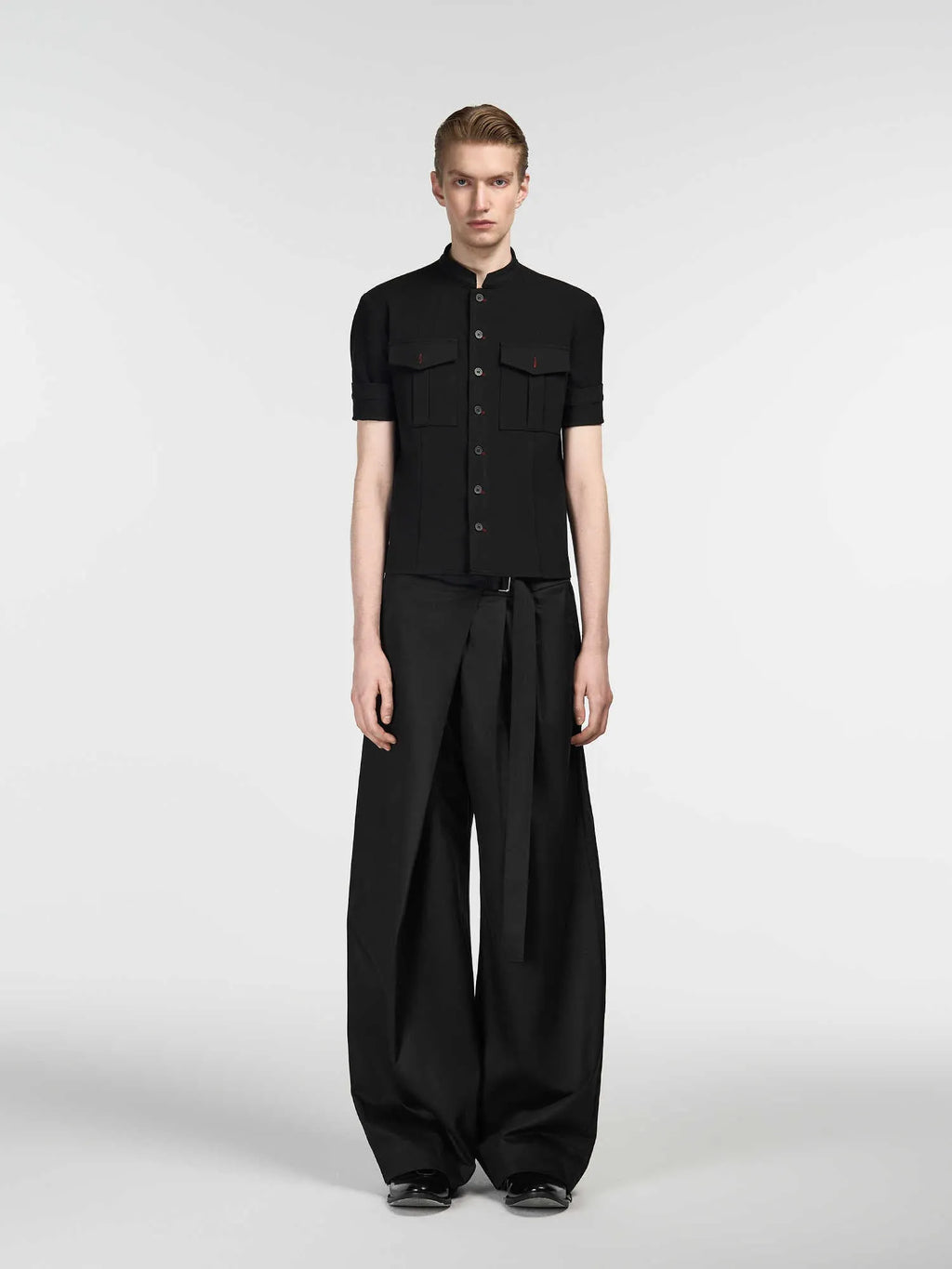 Black straight-leg trousers with a single front pleat and adjustable waistband on a hanger.