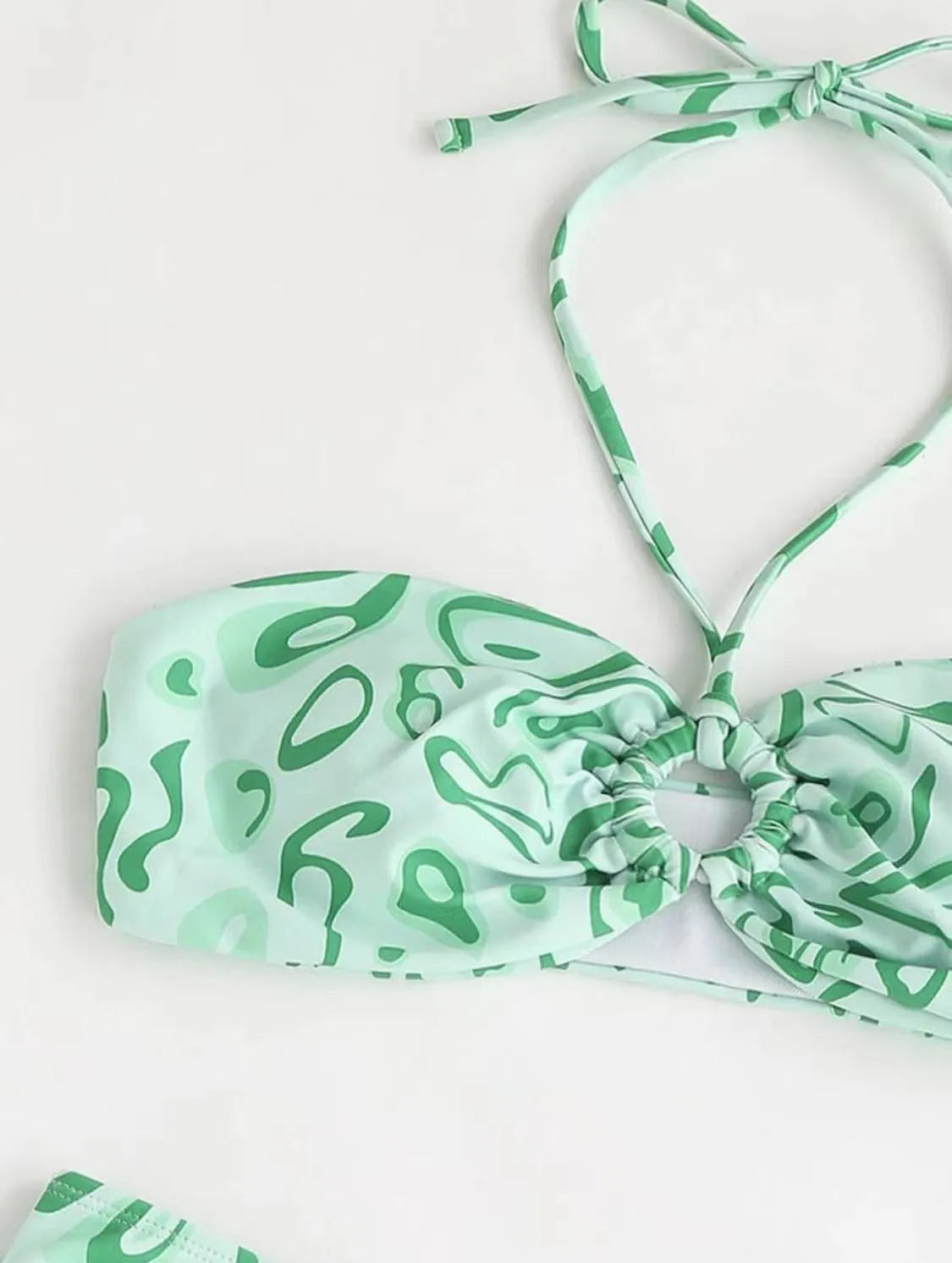 Green floral bandeau bikini swimsuit set with briefs on a neutral background.