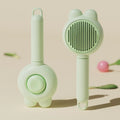 Green self-cleaning pet grooming brush with metal comb and comfort-grip handle on a wooden table.