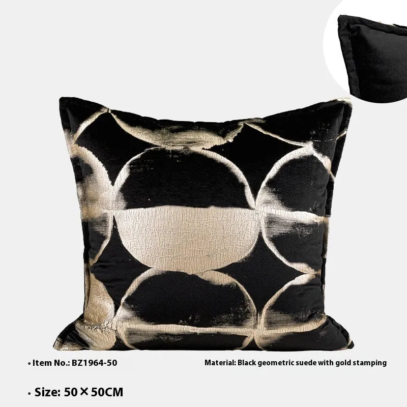 Black and gold abstract pattern decorative flannel pillow with removable cover on a grey sofa.