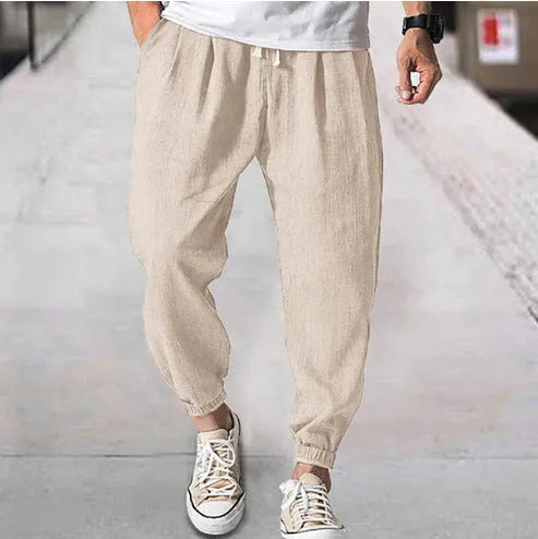 Man modelling loose fit cotton trousers with elasticated ankle cuffs in a light green colour.