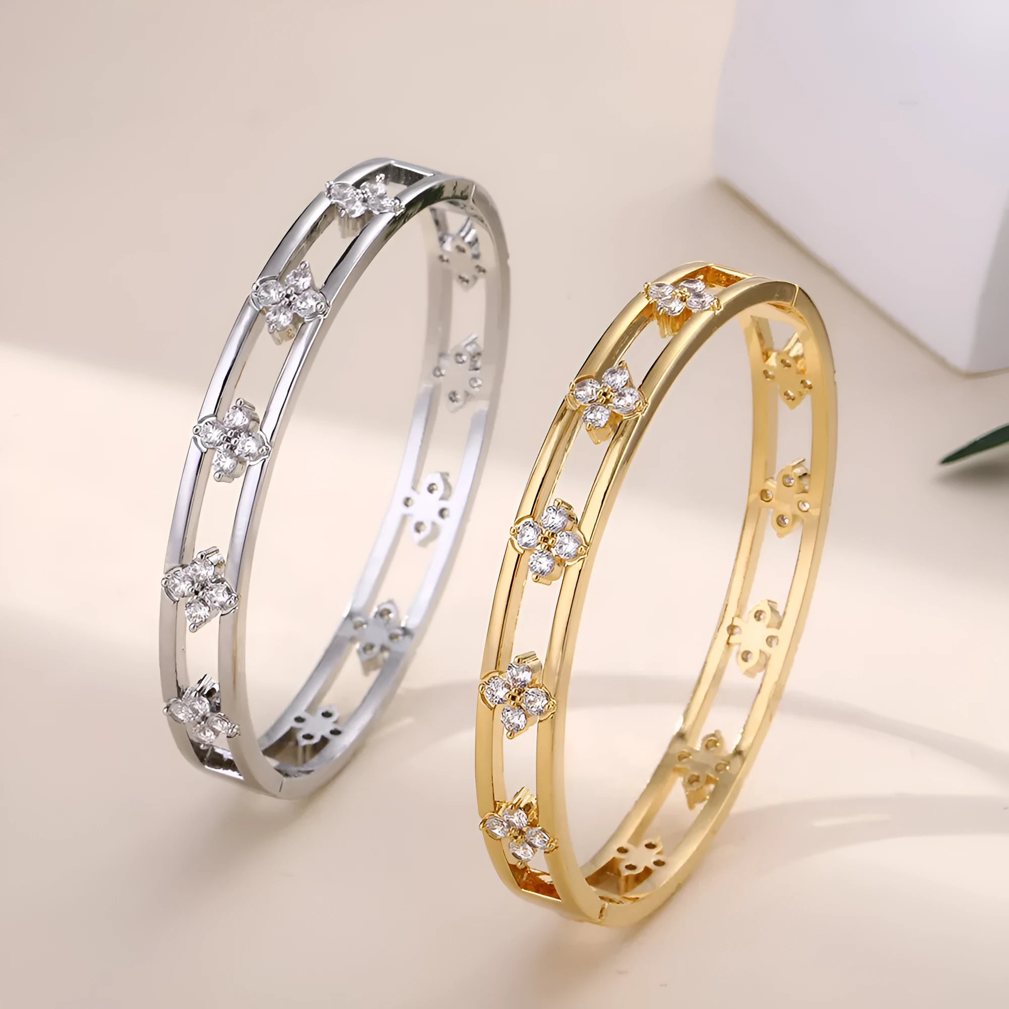 Gold and silver hollow women's bracelets with four-leaf clover zircon charms on a white background.