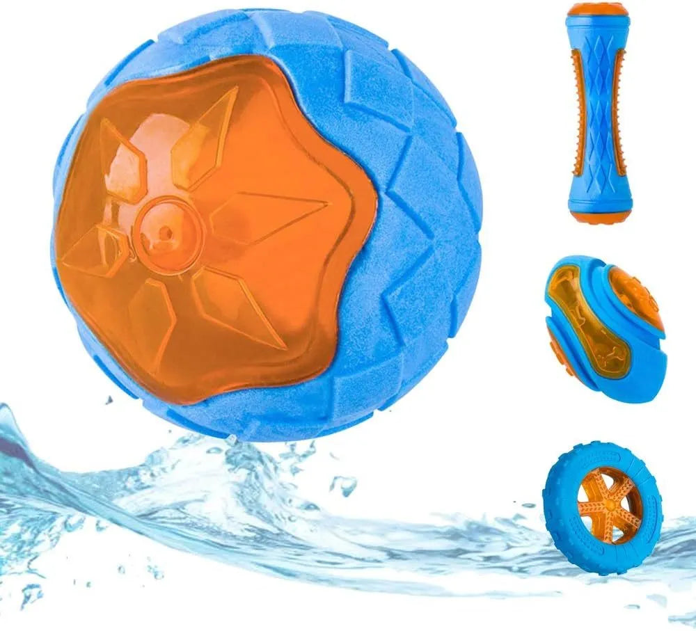 Set of three floating dog toys: a blue squeaky ball, an orange barbell, and red tyres on a beach.