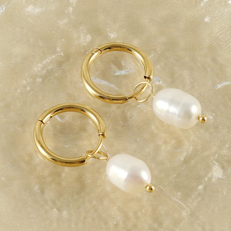 A pair of geometric drop earrings with a gold metal frame and a central freshwater pearl.