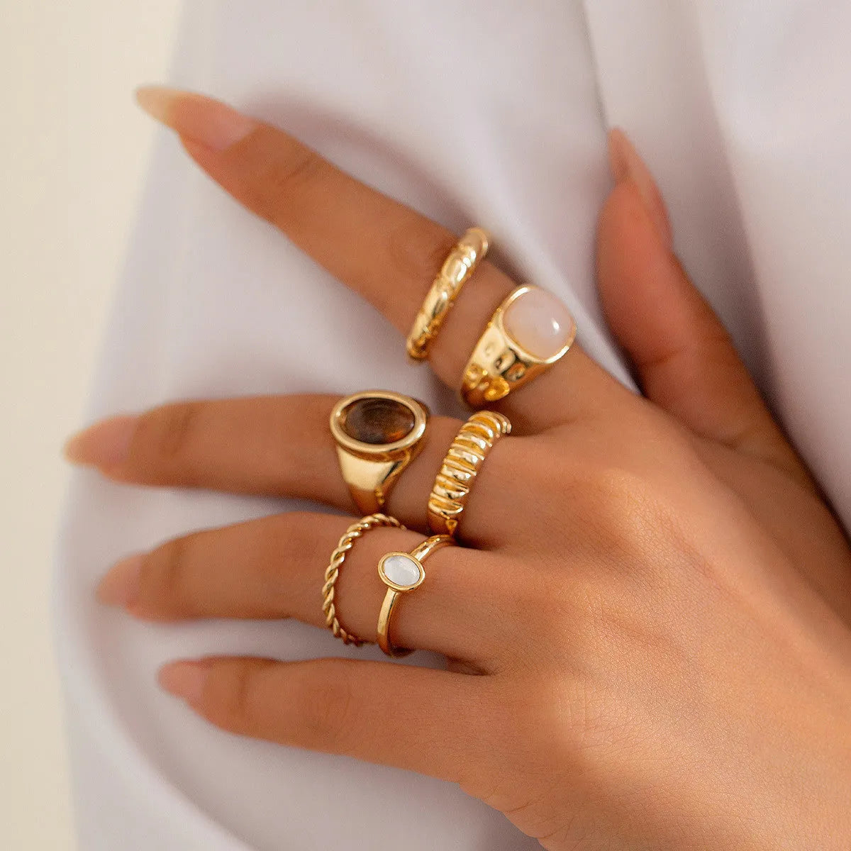 Six geometric alloy rings with light gold electroplated finish arranged as a coordinated set