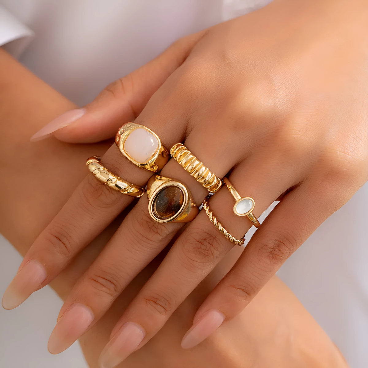 Six geometric alloy rings with light gold electroplated finish arranged as a coordinated set