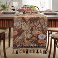 Beige jacquard table runner with floral pattern and long tassels laid on a wooden table.