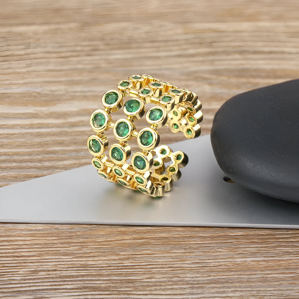 Copper ring with gold plating showing a wide, layered band fully set with green zircon stones.