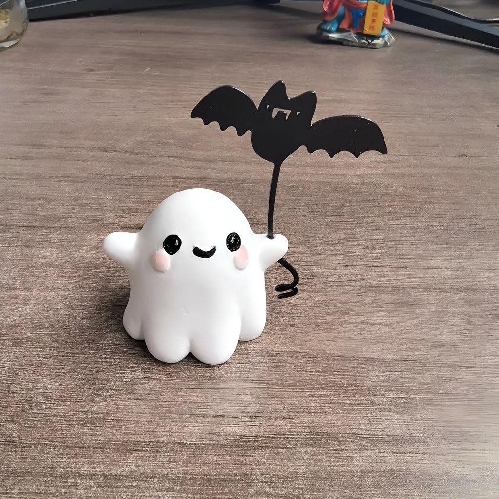 Miniature resin statue of a white ghost dog walking and holding a small black bat, Halloween decoration.