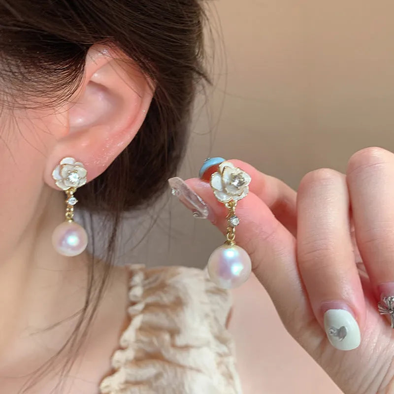 A pair of camellia flower-shaped stud earrings for women in a metallic alloy finish.
