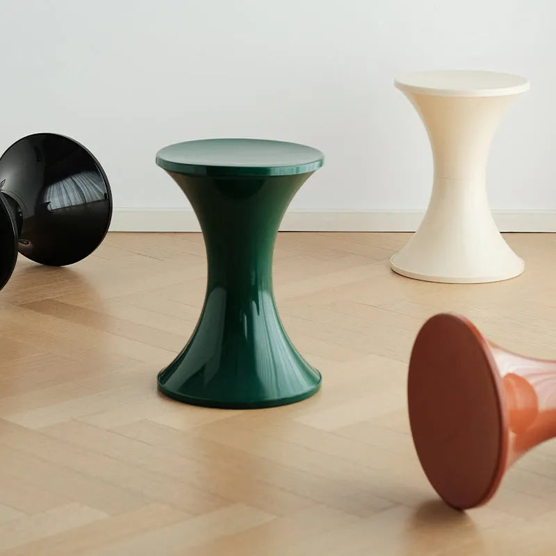 A plastic hourglass-shaped stool for changing shoes, shown in a green colour variant.