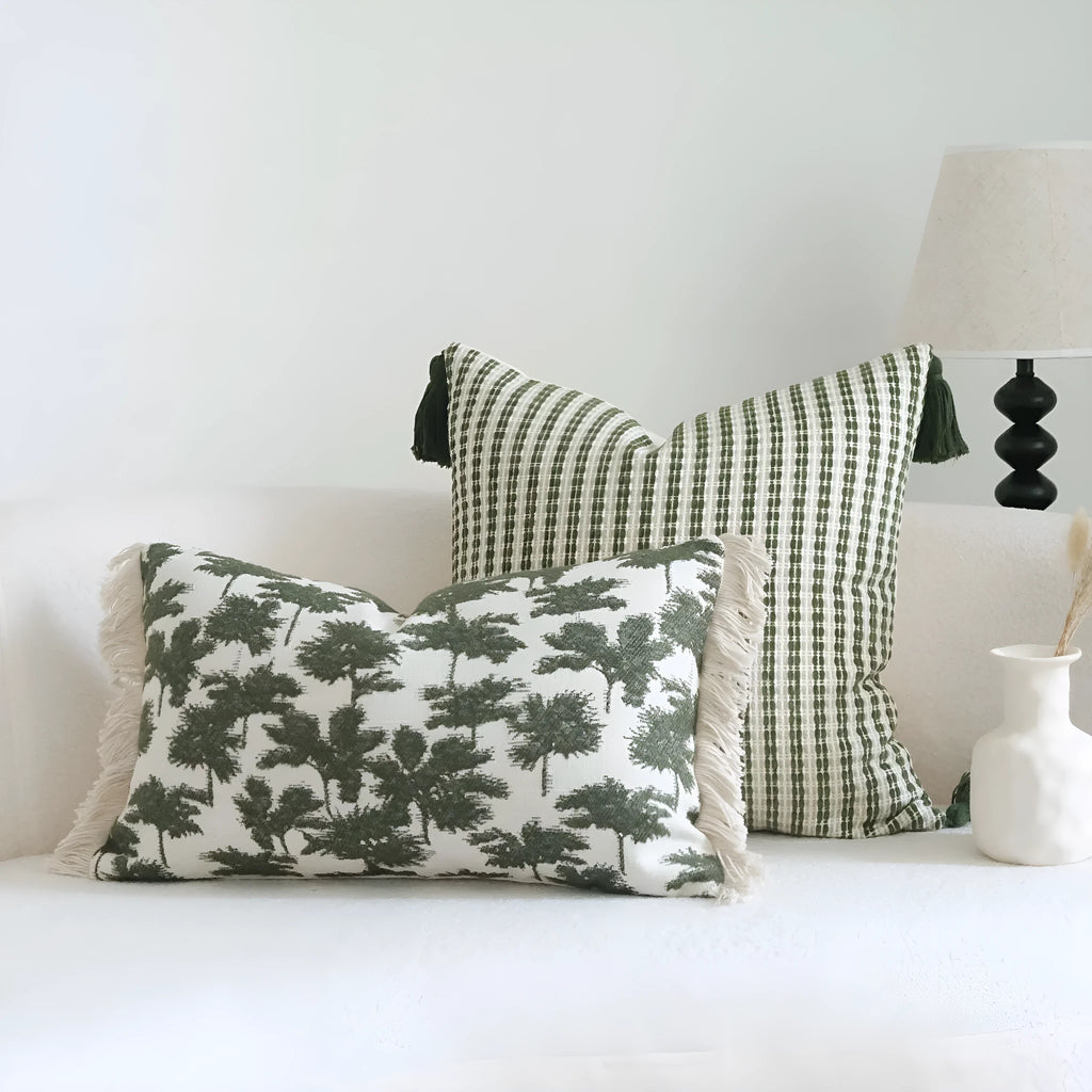 Green patterned cotton linen decorative pillow on a bed, shown in striped, botanical, and leaf designs.