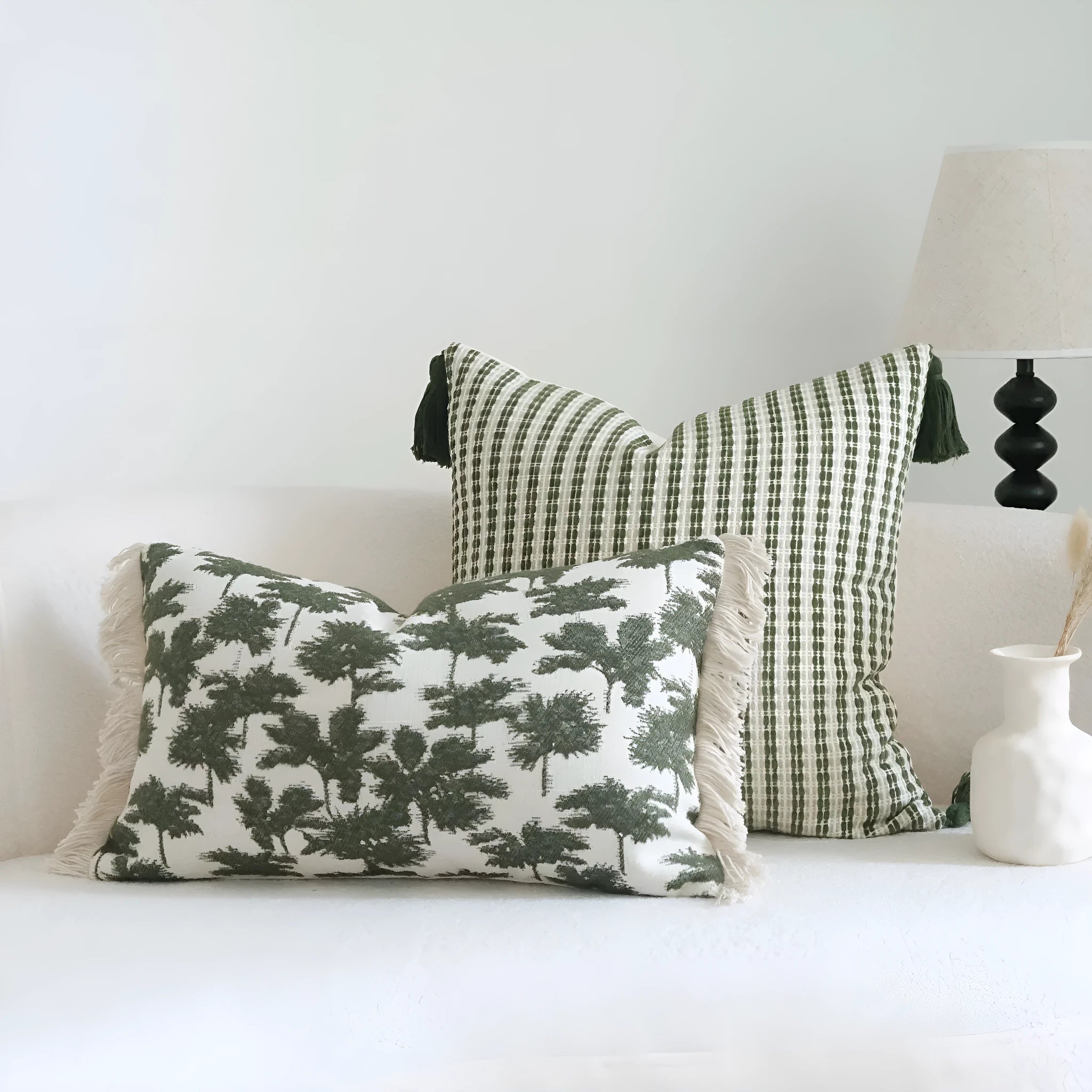 Green patterned cotton linen decorative pillow on a bed, shown in striped, botanical, and leaf designs.