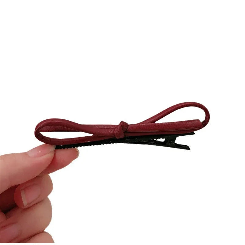 Wine red leather bow hair barrettes shown from multiple angles on dark background