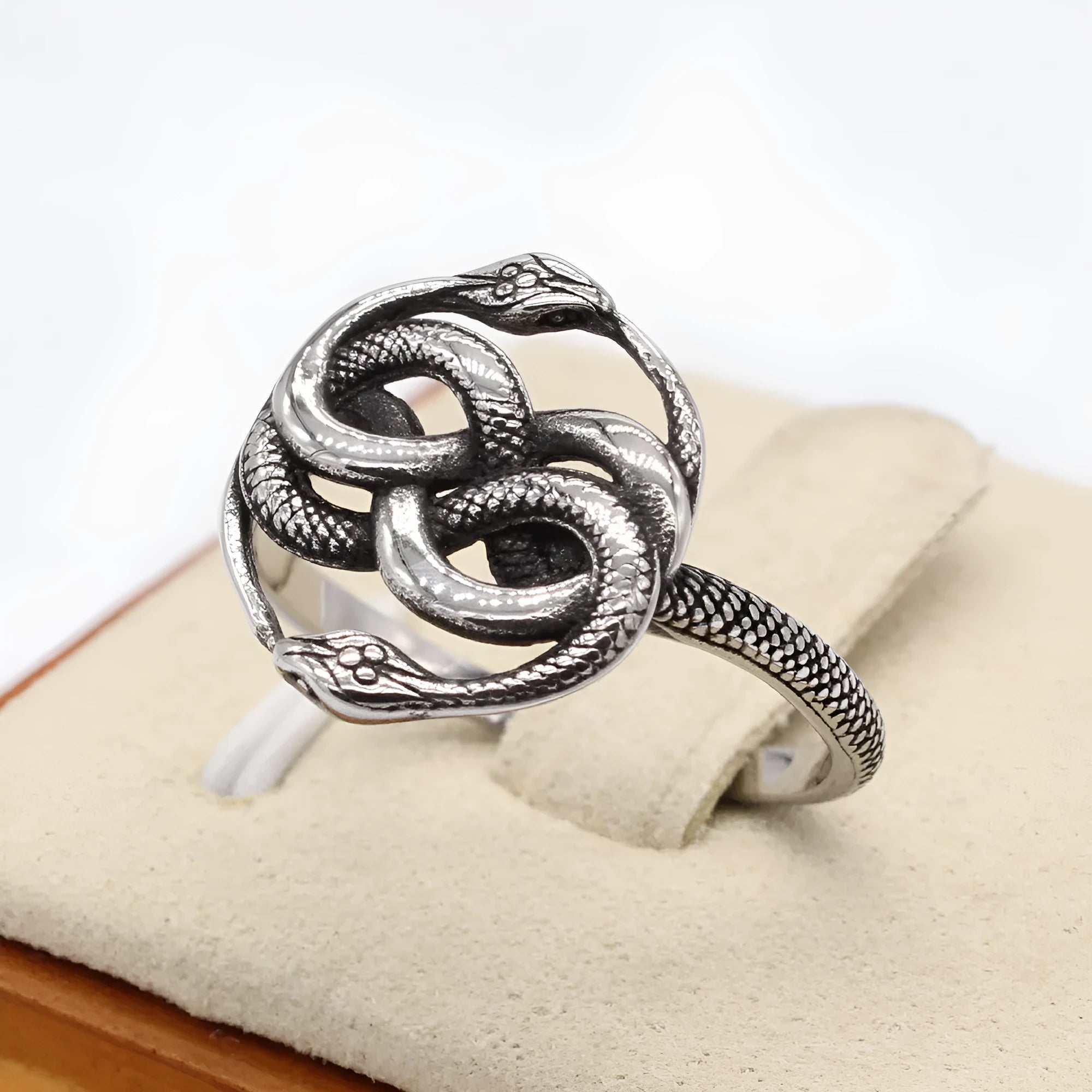 Steel-coloured titanium steel retro ring with a detailed double snake design on a finger.