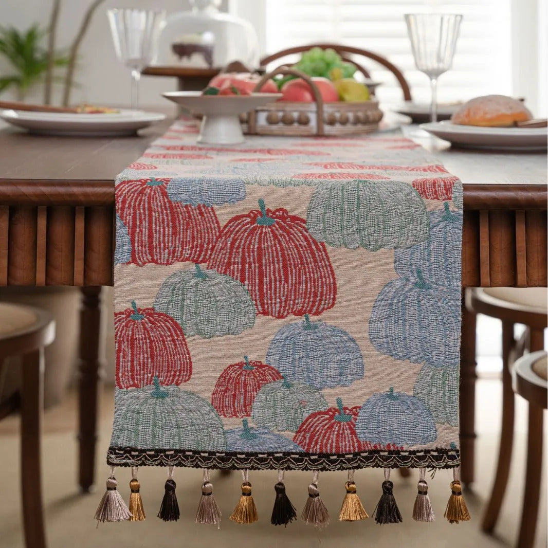 Beige jacquard table runner with floral pattern and long tassels laid on a wooden table.