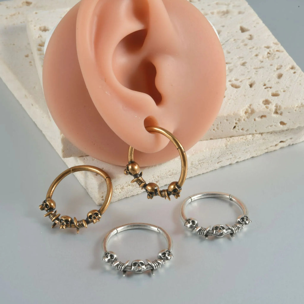Copper puncture earrings in ancient silver and gold featuring single and three ghost head punk designs.