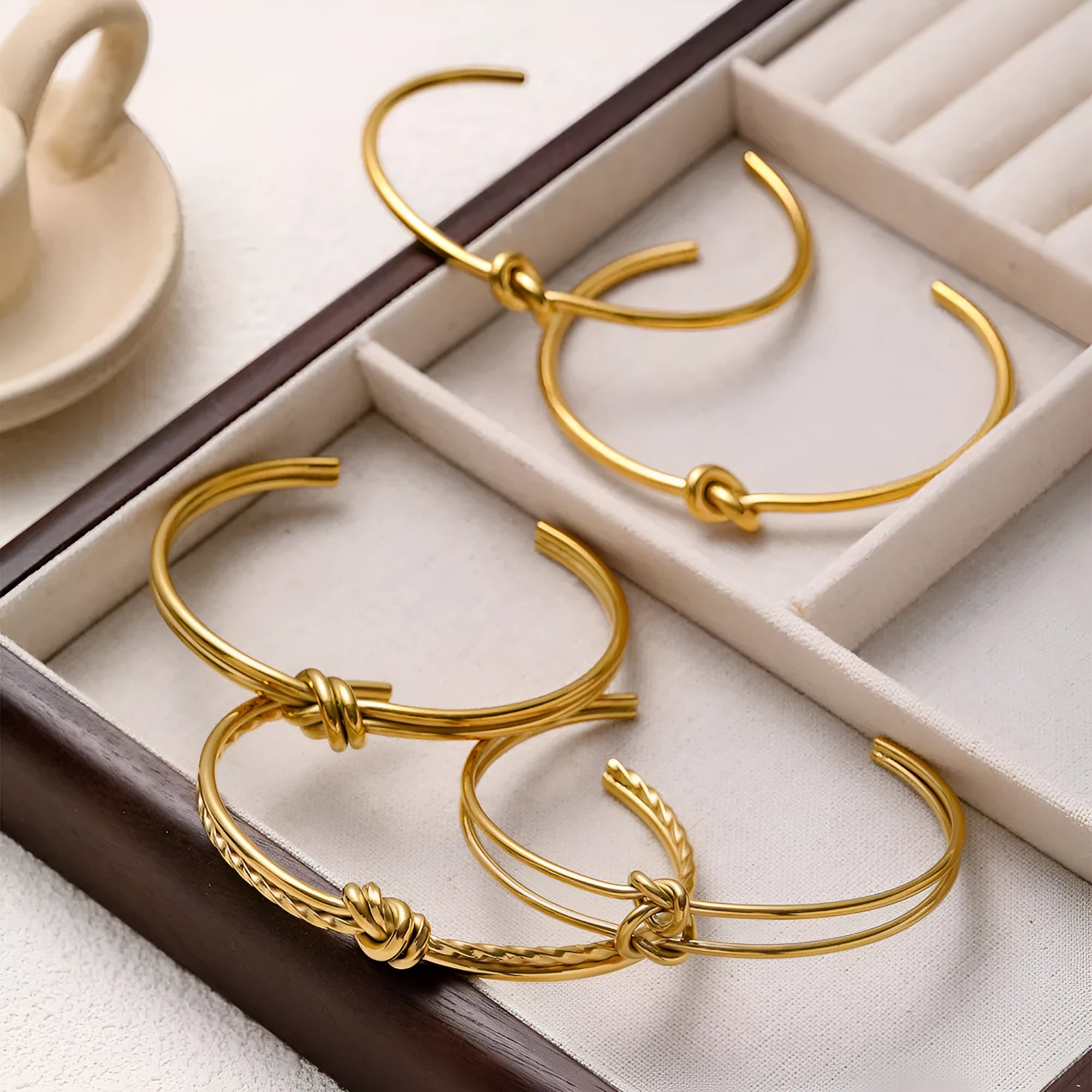 Women's adjustable stainless steel bracelet with C-shaped open design, double-layer construction and knotted detailing in gold or silver finish