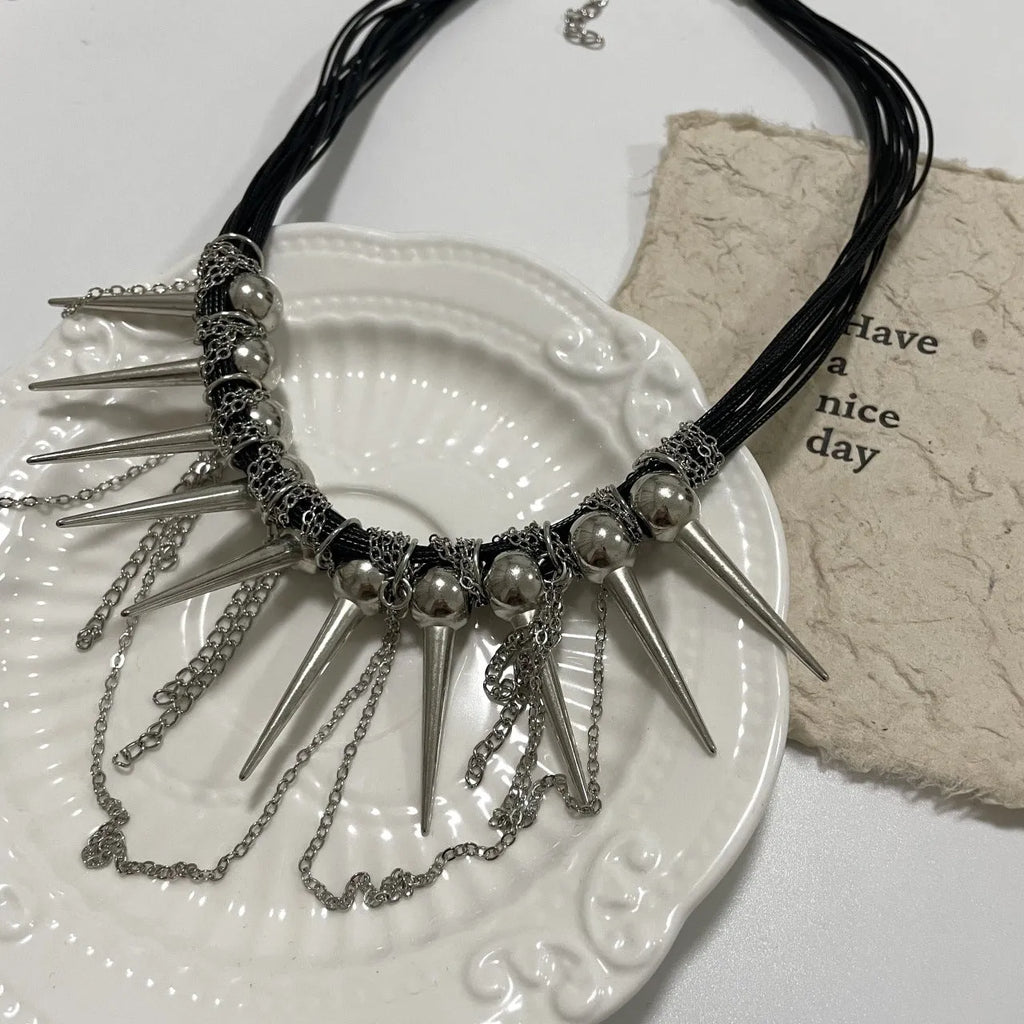 Leather necklace with round beads, a winding tassel, and silver point rivets on a white background.