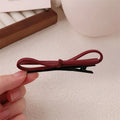 Wine red leather bow hair barrettes shown from multiple angles on dark background