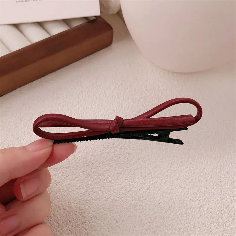 Wine red leather bow hair barrettes shown from multiple angles on dark background