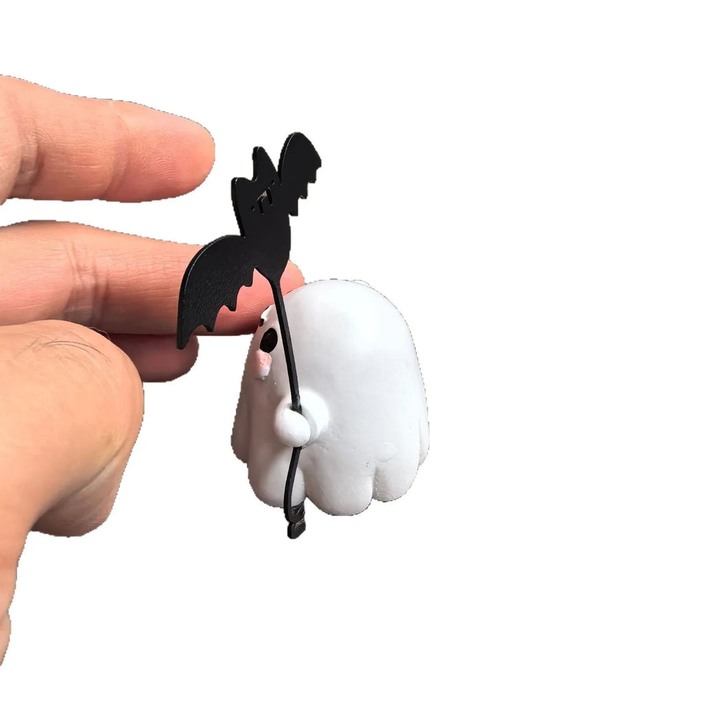 Miniature resin statue of a white ghost dog walking and holding a small black bat, Halloween decoration.
