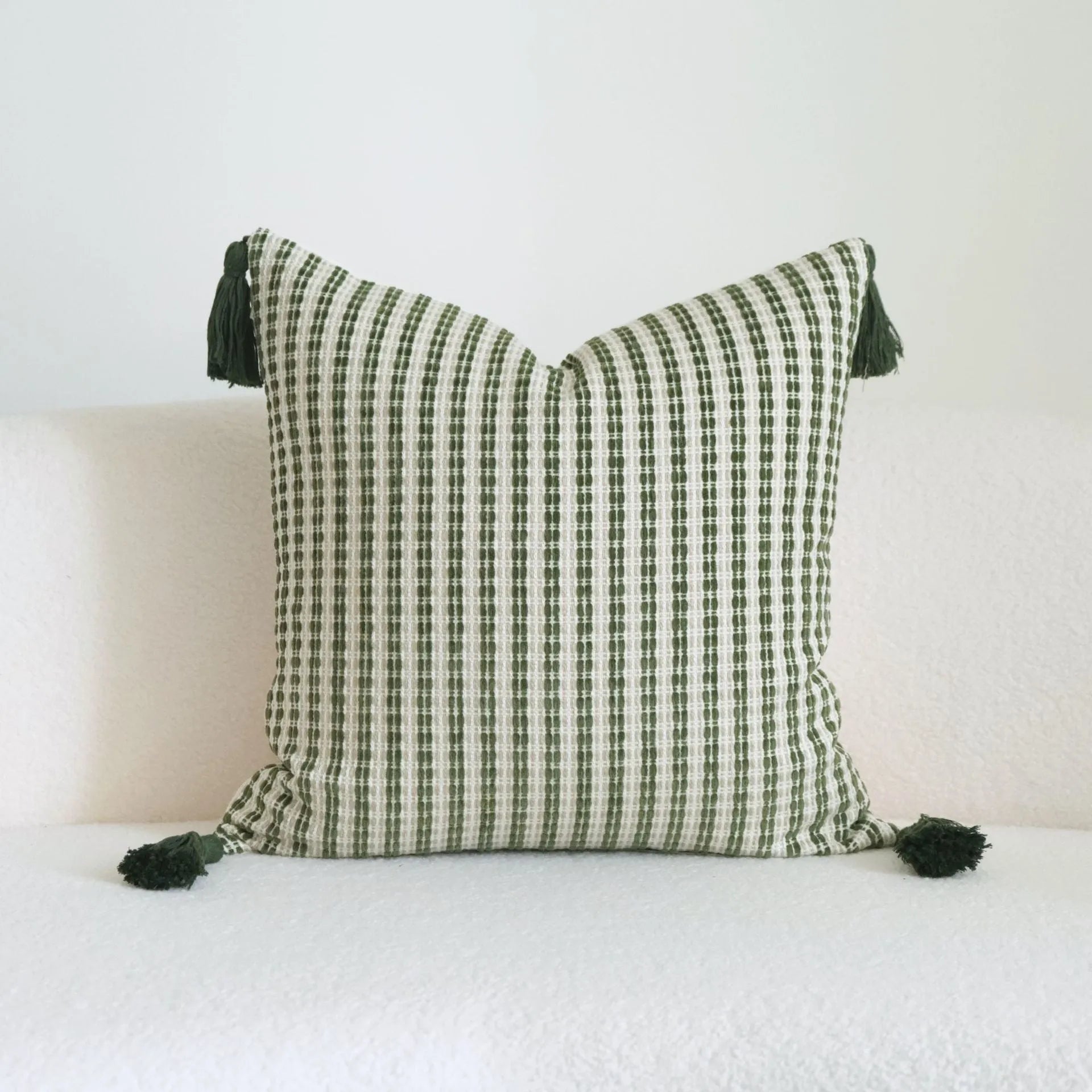 Green patterned cotton linen decorative pillow on a bed, shown in striped, botanical, and leaf designs.