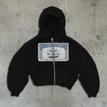 A man and woman wearing a loose fit black zip-up hoodie jacket with a hood and zip pockets.