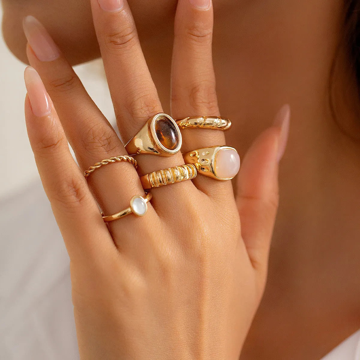 Six geometric alloy rings with light gold electroplated finish arranged as a coordinated set