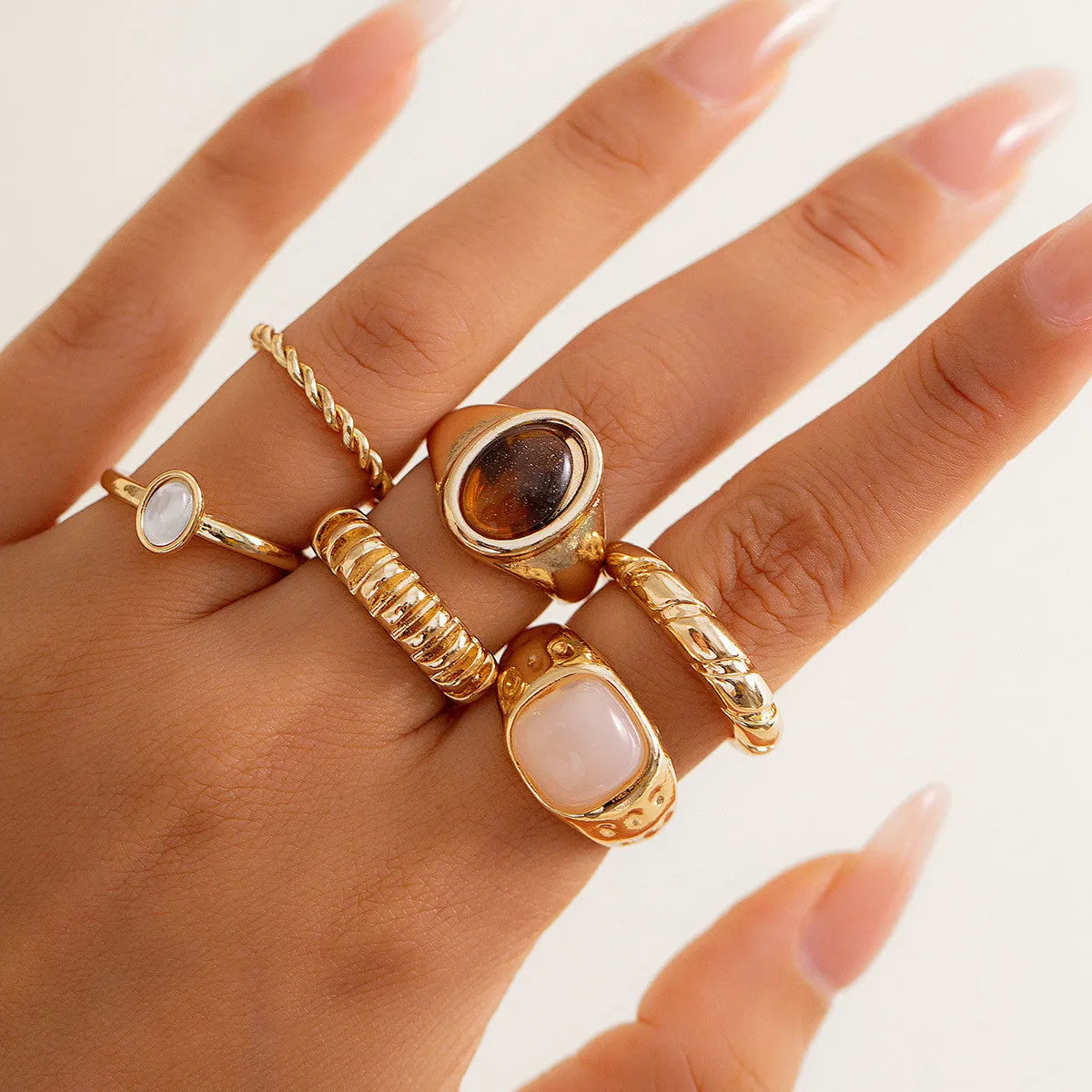 Six geometric alloy rings with light gold electroplated finish arranged as a coordinated set