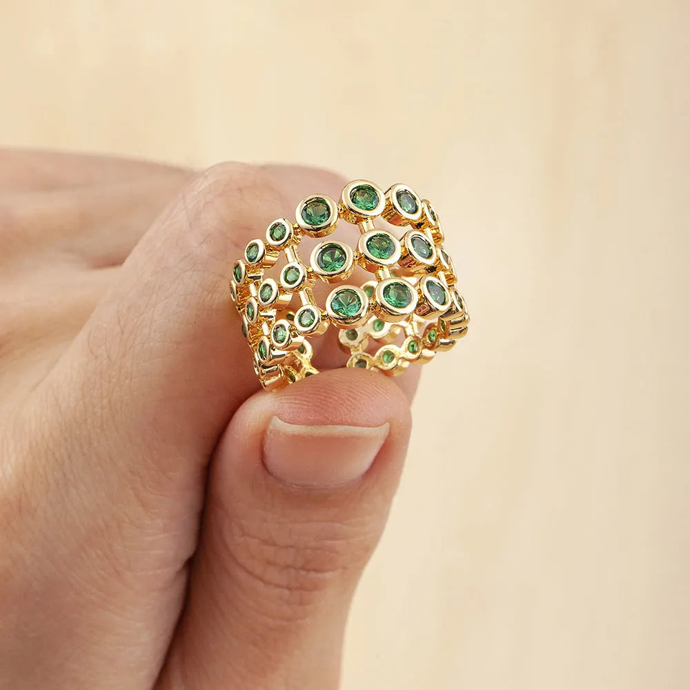 Copper ring with gold plating showing a wide, layered band fully set with green zircon stones.