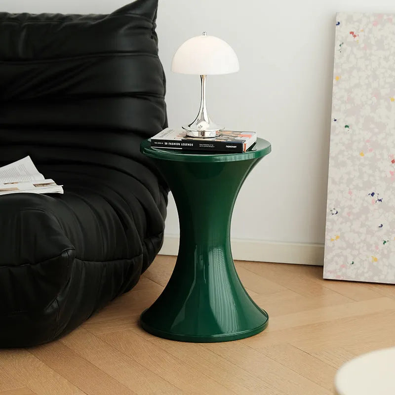 A plastic hourglass-shaped stool for changing shoes, shown in a green colour variant.