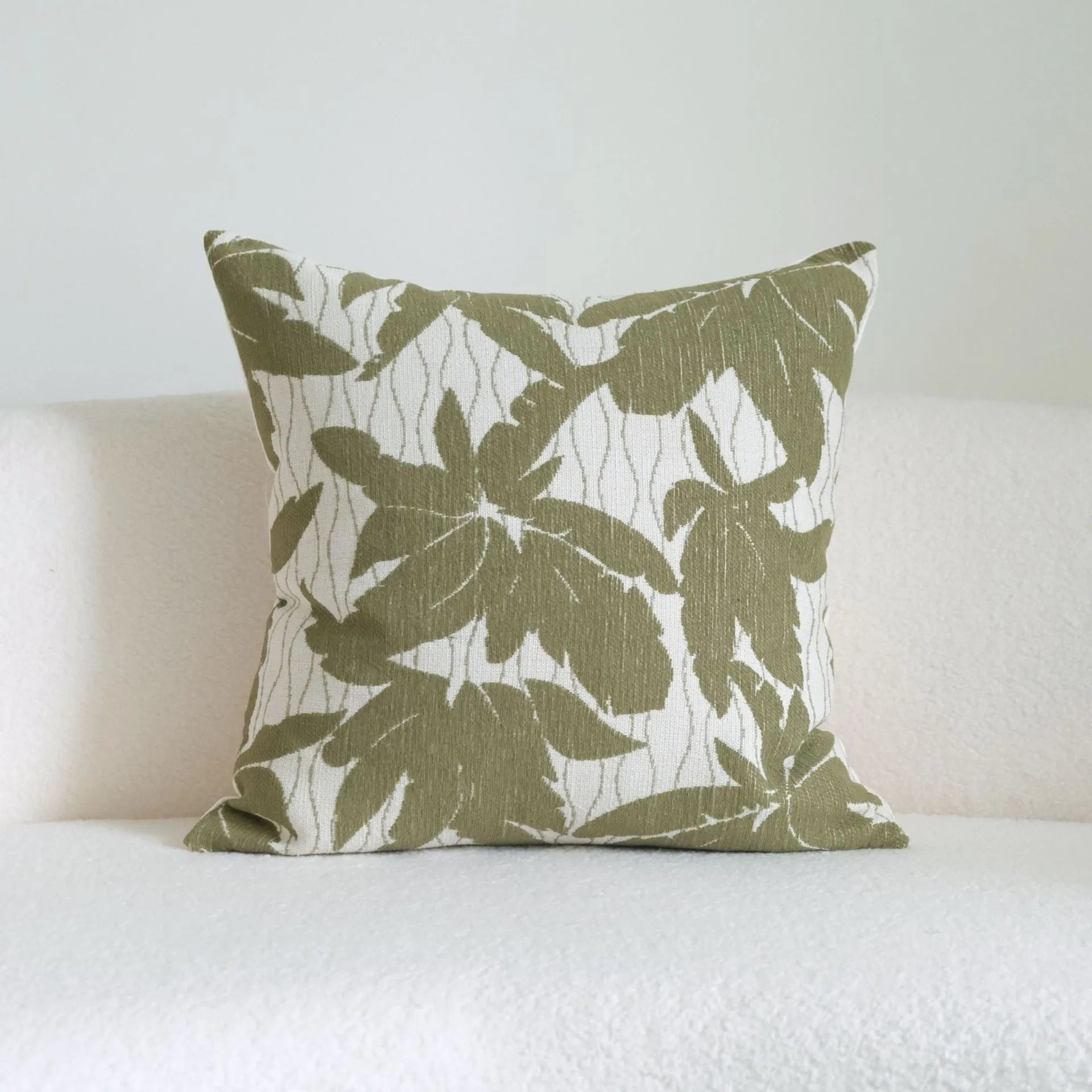 Green patterned cotton linen decorative pillow on a bed, shown in striped, botanical, and leaf designs.