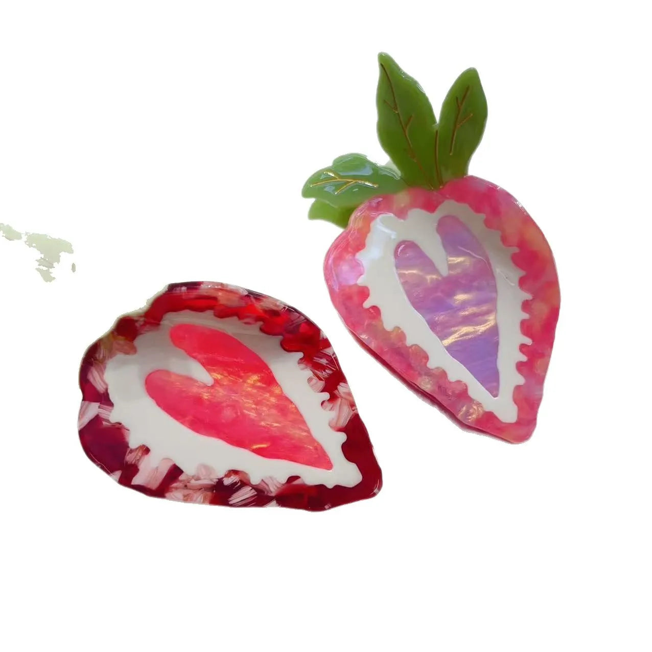 Close-up of a red strawberry-shaped hair clip with a green leaf, on a white background.