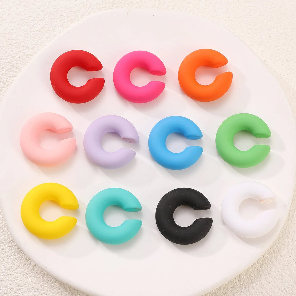 C-shaped clip-on earrings with round geometric shape and matte coarse finish in assorted candy colours.