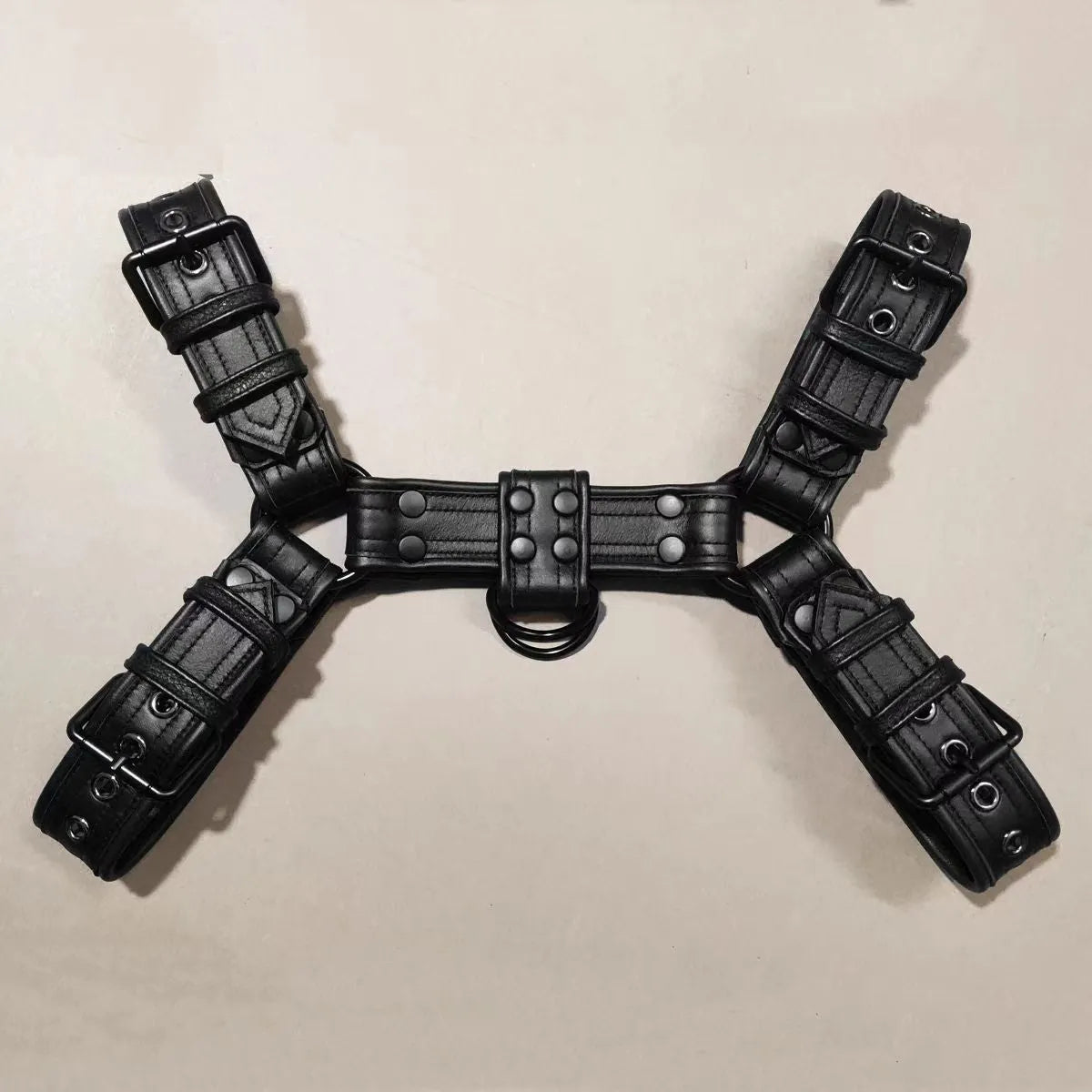 Black leather chest strap with metal buckle and rivet detailing for adult male costume wear