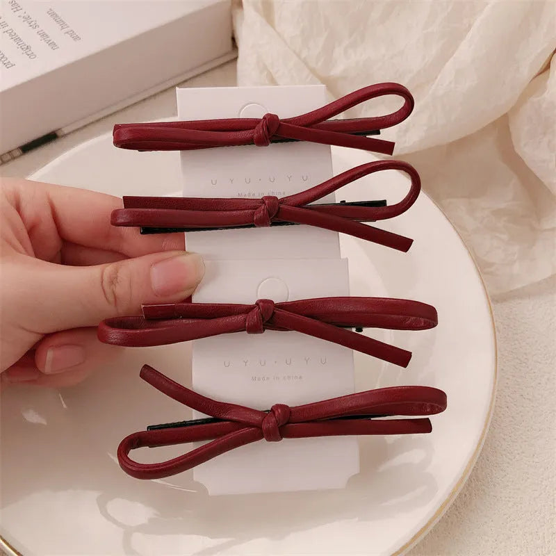 Wine red leather bow hair barrettes shown from multiple angles on dark background