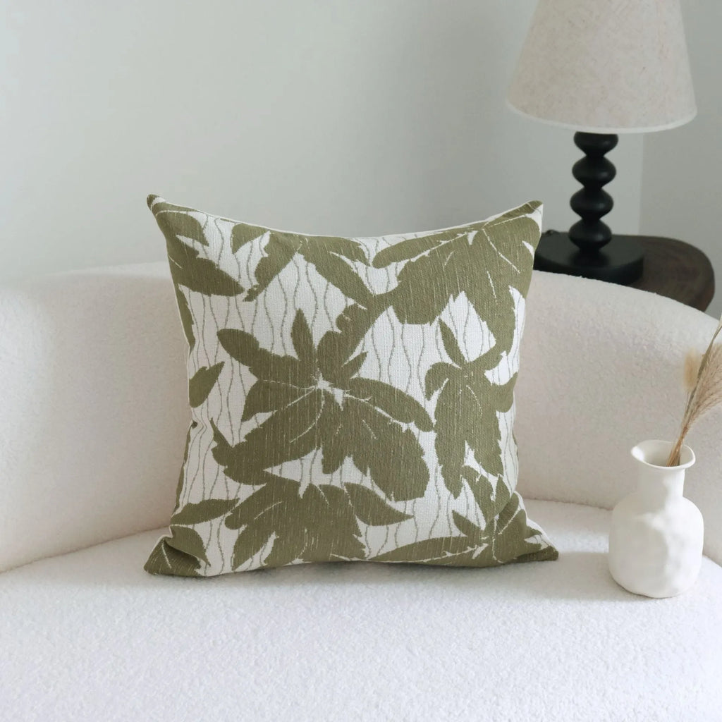 Green patterned cotton linen decorative pillow on a bed, shown in striped, botanical, and leaf designs.