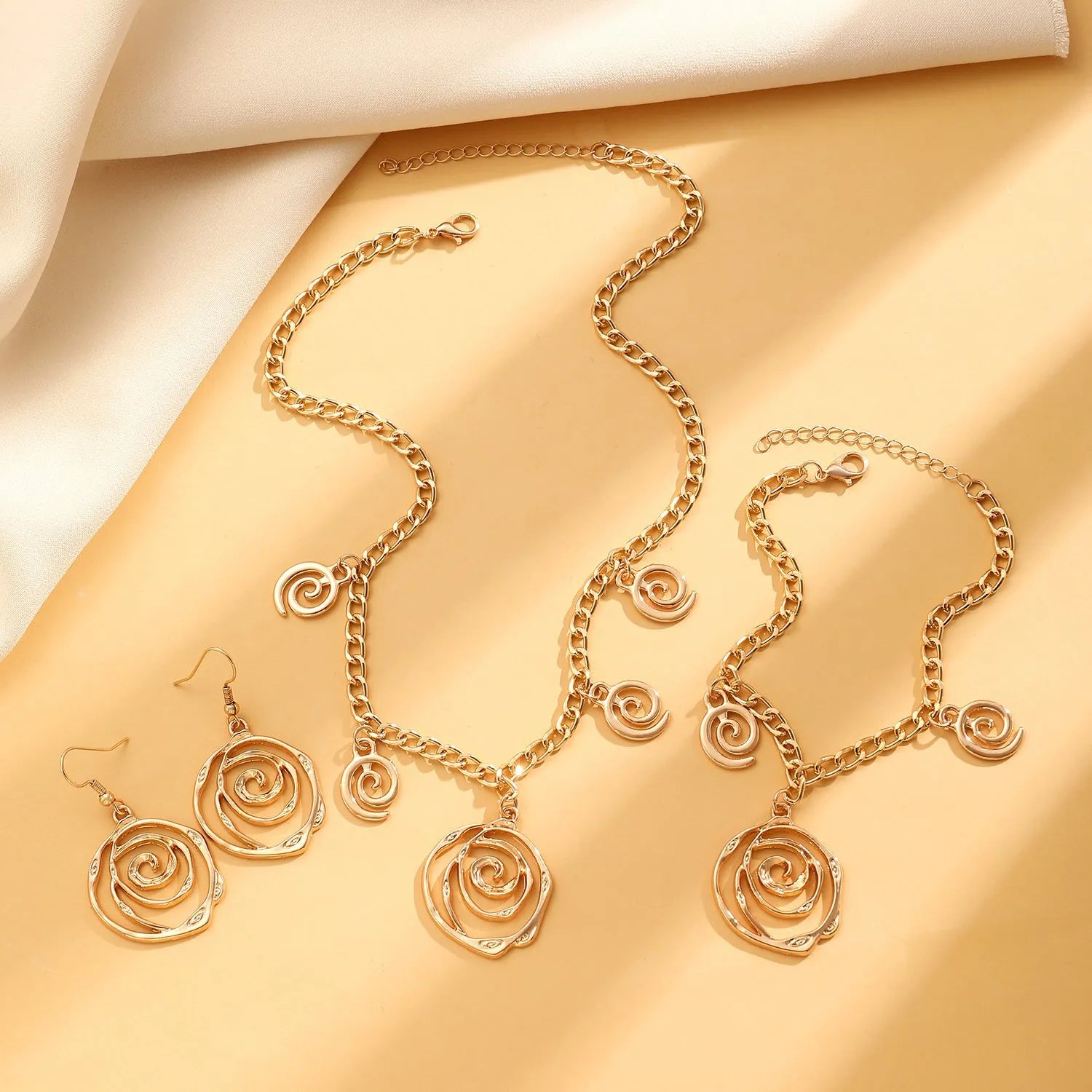 Gold or silver electroplated alloy jewellery set with spiral donut geometric shapes including necklace bracelet and ear hooks