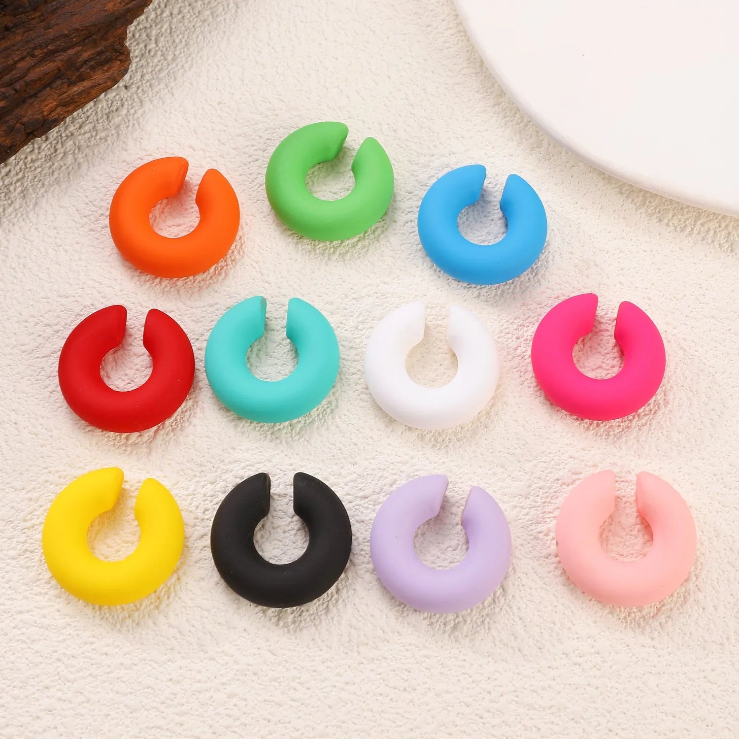 C-shaped clip-on earrings with round geometric shape and matte coarse finish in assorted candy colours.